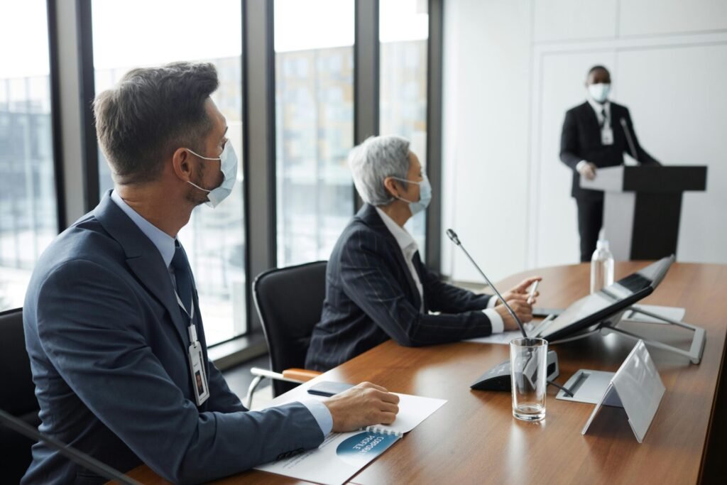 Business professionals in a meeting room wearing face masks for safety.
